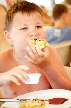 Boy eats a pizza in summer cafe on a beach Stock Photos
