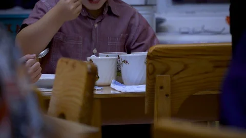 The boy eats porridge in kindergarten. It is too tasty, you need to eat it quick Video stock 99729418