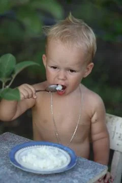 Boy eats porridge Stock Photos