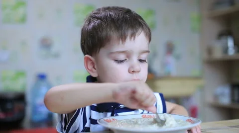 The boy eats porridge spoon full Stock Footage 57749716