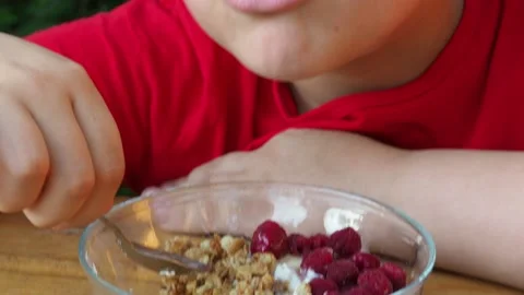 Boy eats proper nutrition and healthy breakfast bowl of oat granola with yogurt 動画素材 168019172