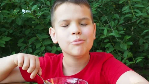 Boy eats proper nutrition and healthy breakfast bowl of oat granola with yogurt 動画素材 168019183