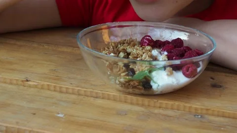 Boy eats proper nutrition and healthy breakfast bowl of oat granola with yogurt 動画素材 168019193