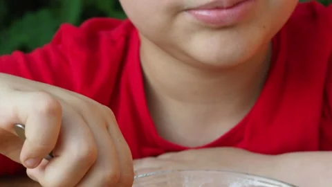 Boy eats proper nutrition and healthy breakfast bowl of oat granola with yogurt 動画素材 168019206