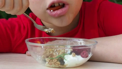 Boy eats proper nutrition and healthy breakfast bowl of oat granola with yogurt 動画素材 168019212