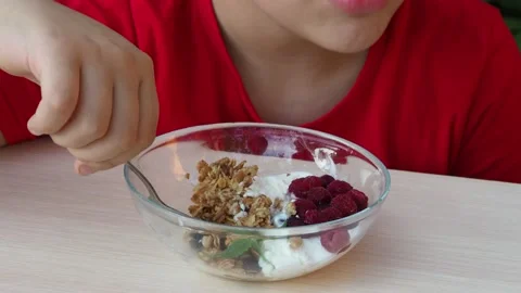 Boy eats proper nutrition and healthy breakfast bowl of oat granola with yogurt 動画素材 168019224