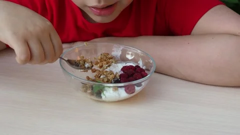 Boy eats proper nutrition and healthy breakfast bowl of oat granola with yogurt 動画素材 168019226