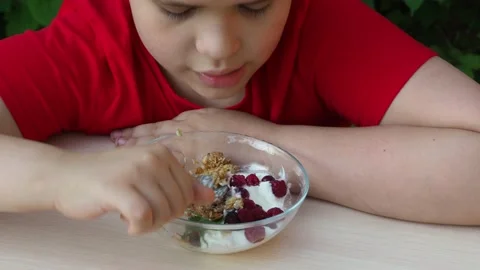 Boy eats proper nutrition and healthy breakfast bowl of oat granola with yogurt 動画素材 168019233