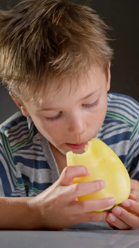 A boy eats a ripe yellow bell pepper. Eat raw vegetables and fruits. Stock Footage 316831292