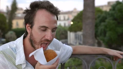 Boy eats Sicilian Food Bronte Pistachio Arancino in Catania Sicily at Sunset Stockbeeldmateriaal 209660144
