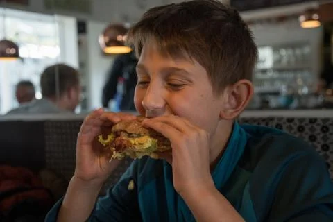 A boy eats staisfied a big burger Foto stock