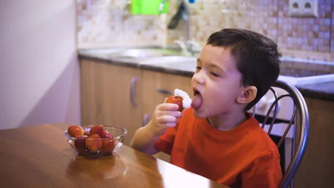A boy eats strawberries with cream, with which his mother wateres strawberries Stock Footage 169527958