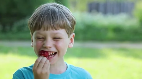 A boy eats strawberries on the street Stock Footage 246443174