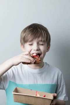 The boy eats a sweet Belgian waffle, closing his eyes in pleasure Stock Photos