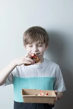 The boy eats a sweet waffle, closing his eyes in pleasure,portrait Stock Photos