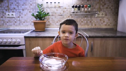 A boy eats tasteless soup from water, because he does not feel the taste Stock Footage 169580499