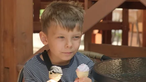 The boy eats two ice creams. Close-up. Video stock 245286964