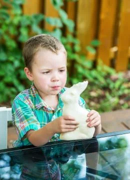Boy eats a white chocolate bunny Stock Photos