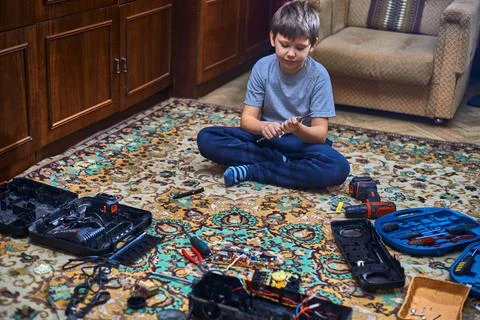 , A boy of eight years old disassembles the old radio, sitting on the carpet  Stock Photos