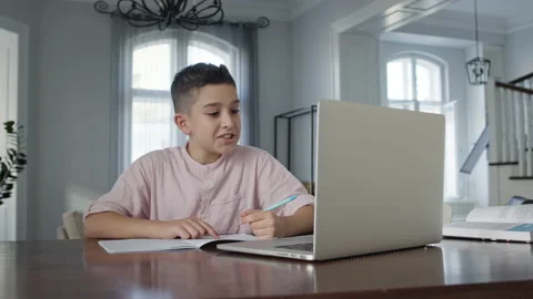 Boy Of Eight Years Sitting In Front Of Laptop At The Table. He Writes In 스톡 동영상 146470490