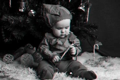Boy in a elf costume sits under a Christmas tree with a Lollipop Stock Photos