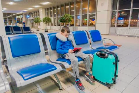 Boy in an empty airport one waits for the plane and plays in his favorite gadget Stock-Fotos