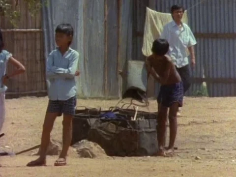 Boy emptying trash from a tin and joining his friend for a playful time Stock Footage 79880446