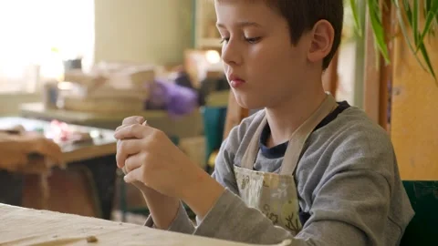 The boy is engaged in clay modeling in a ceramics class. Children's leisure Stock Footage 303760308