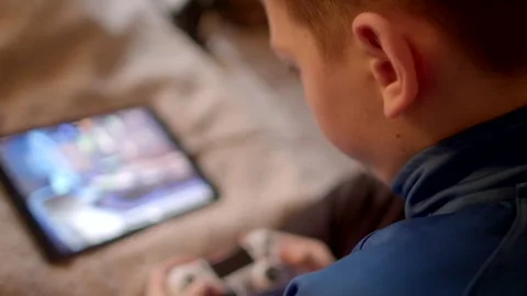 A boy is engaged with his tablet, exploring digital content while relaxing comfo Stock-Footage 295932367
