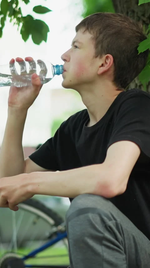 Boy Enjoying Refreshing Water Break Under Tree After Bike Ride Stock-Footage 310813125