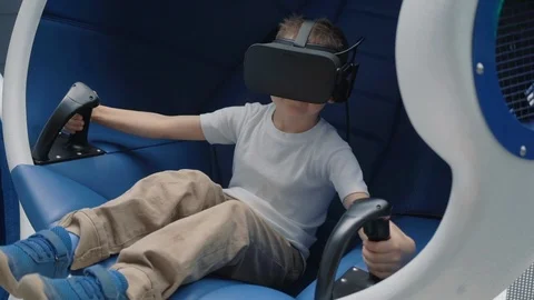 Boy enjoying virtual reality attraction using VR headset in a moving interactive Stock Footage 106750154