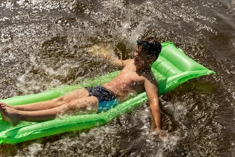 A boy enjoys floating in a river under the warm sun Stock Photos