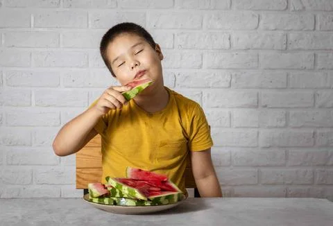 Boy enjoys a refreshing slice of watermelon, embodying the joy of consuming Stock Photos