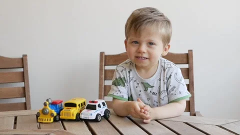 Boy enjoys time with a toy train and cars, creating joyful play. Toy captures Video stock 317988475