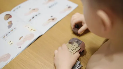Boy enthusiastically assembles educational toy construction set with Stock Footage 283407614