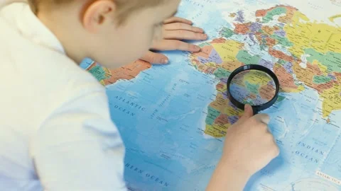 The boy examines the map using a magnifying glass. Stock-Footage 151113975