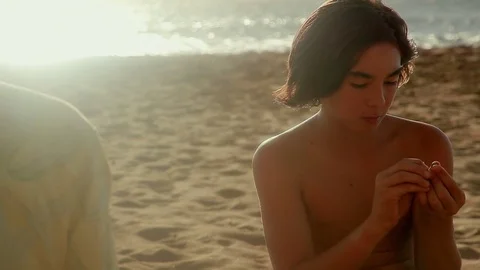 A boy examines a shell on the beach in Hawaii. Stock Footage 84231564