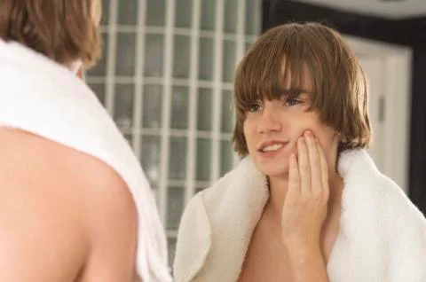 Boy examining his face in the bathroom mirror Stock Photos