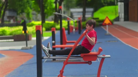Boy Exercising on Outdoor Rowing Machine in Public Fitness Park, Healthy Stock Footage 338013701