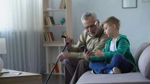 Boy explaining to grandpa how to use cell phone, simple technologies for old man Video stock 90027562
