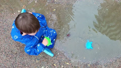 The boy is exploring the muddy puddle with his hand, feeling the texture of the Stock Footage 249475139