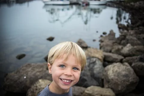 Boy exploring on the rocks at the harbor Stock Photos