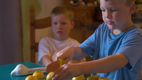 Boy with an Expressive Face Cutting Lemons for Lemonade Stock Footage 94394991
