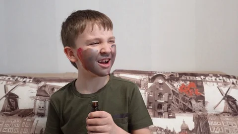 Boy with face paint sniffing a bottle of medicine and Hamming Video stock 127111865