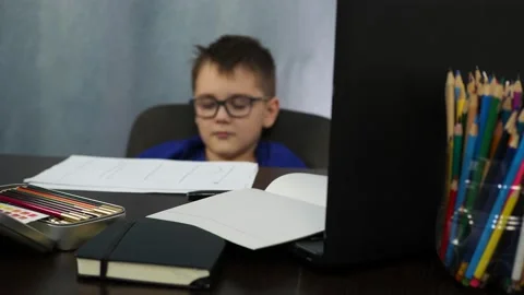 The boy falls asleep sitting at the table. tedious remote study Stock Footage 145276397