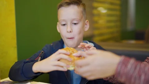 A boy in a fast food cafe. Eating burger... | Stock Video | Pond5