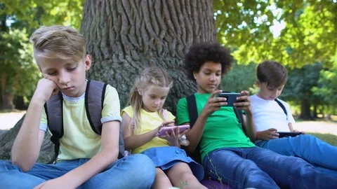 Boy feeling bored while friends playing games on phones instead of communication Stock-Footage 117200541