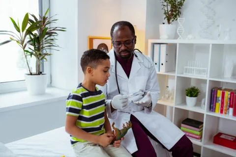 Boy feeling curious while looking at thermometer visiting doctor Foto stock