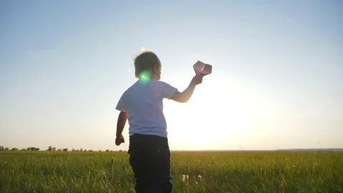 A boy in the field at sunset runs and throws a paper plane. The concept of a 스톡 동영상 120059629