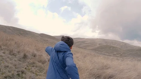 A boy on field with tall grass run to horizon with hills. Slow motion video Stock Footage 87317025